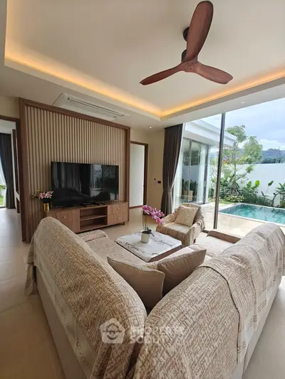 Luxurious living room with pool view, elegant decor, and modern ceiling fan