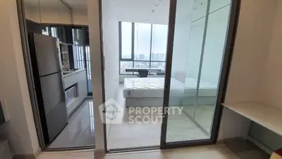 Modern apartment with glass partition, sleek kitchen, and city view.