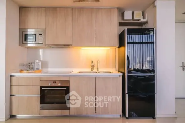 Modern kitchen with sleek appliances and wooden cabinetry, featuring a built-in oven and microwave.