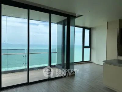Stunning ocean view from modern apartment with floor-to-ceiling windows and spacious balcony.