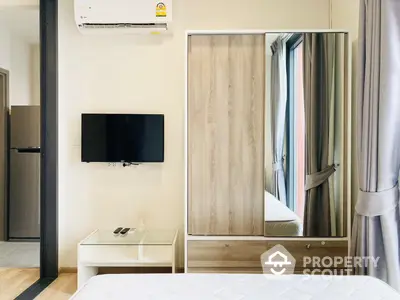 Modern minimalist bedroom with sleek wooden wardrobe, mounted flat-screen TV, and air conditioning unit, perfect for urban living.