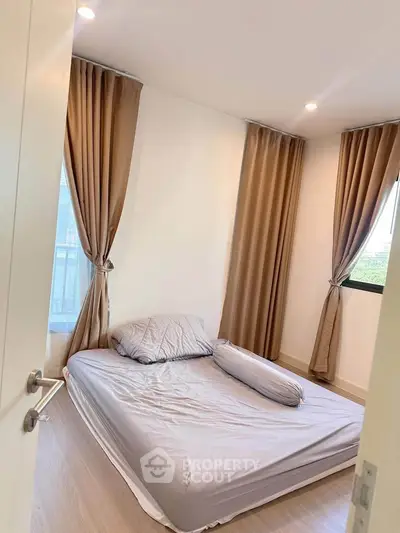 Cozy bedroom with natural light and elegant curtains, perfect for relaxation.