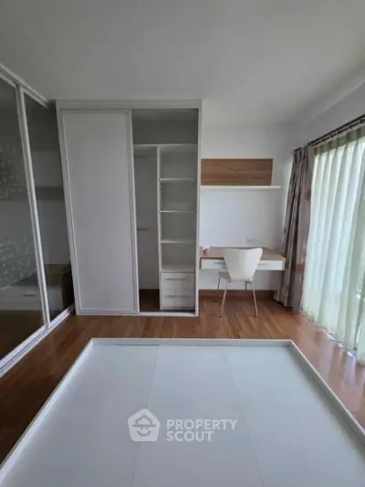 Modern bedroom with built-in wardrobe and study desk, featuring floor-to-ceiling windows for natural light.