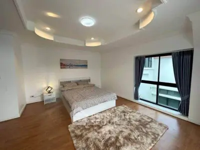 Spacious bedroom with modern decor and large window for natural light.