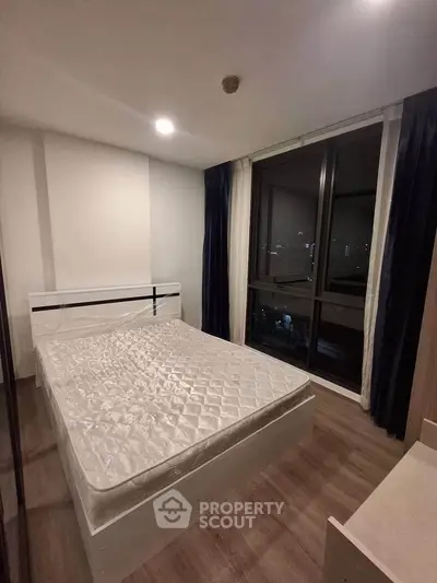 Modern bedroom with large window and city view, featuring a comfortable bed and stylish decor.