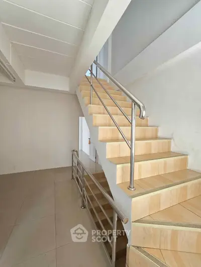 Modern staircase with sleek metal railing in a bright, minimalist interior space.