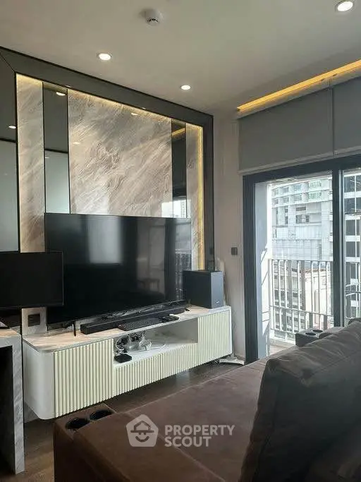 Modern living room with sleek TV setup and balcony view in urban apartment.