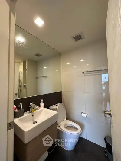 Modern bathroom with sleek fixtures and large mirror in a contemporary apartment.
