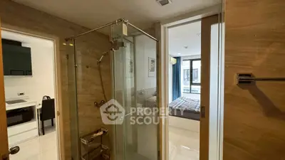 Modern apartment interior with glass shower and bedroom view