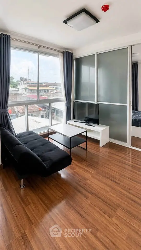 Modern living room with large windows, sleek furniture, and wooden flooring offering a bright and airy ambiance.