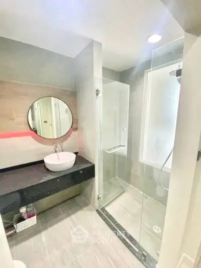 Modern bathroom with glass shower and round mirror, sleek design