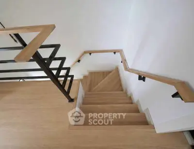 Modern wooden staircase with sleek metal railings in a contemporary home interior.