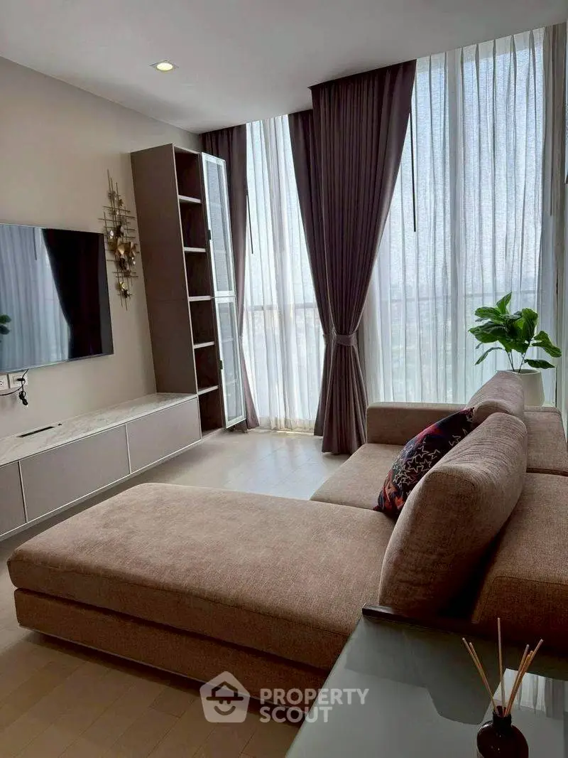 Modern living room with large windows, stylish sofa, and elegant decor in a high-rise apartment.