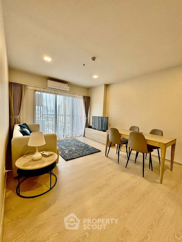 Modern living room with cozy seating and dining area, featuring a large window for natural light.