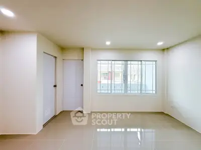 Spacious empty room with large window and glossy tiled floor