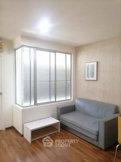 Modern living room with cozy sofa and large window, featuring elegant wooden flooring.