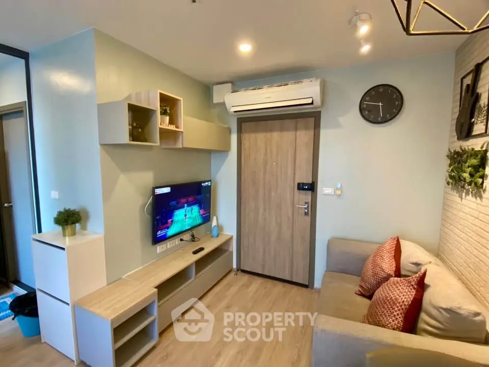 Modern living room with sleek furniture and wall-mounted TV, featuring stylish decor and air conditioning.