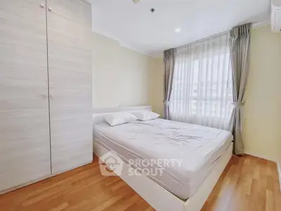 Bright and cozy bedroom with wooden flooring and large window.