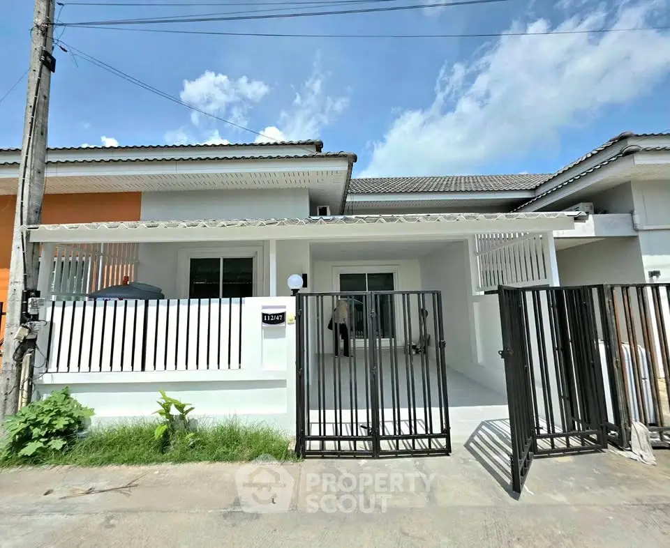 Charming single-story home with gated entrance and modern facade under a clear blue sky.