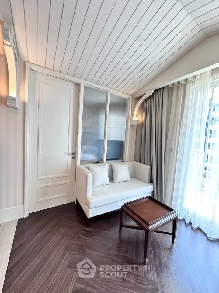 Charming living room with elegant white sofa, wooden table, and large window for natural light.