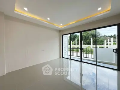 Spacious modern living room with large glass doors opening to a scenic view, featuring elegant recessed lighting.