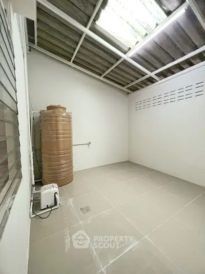 Spacious utility room with water tank and tiled flooring, ideal for storage or laundry setup.