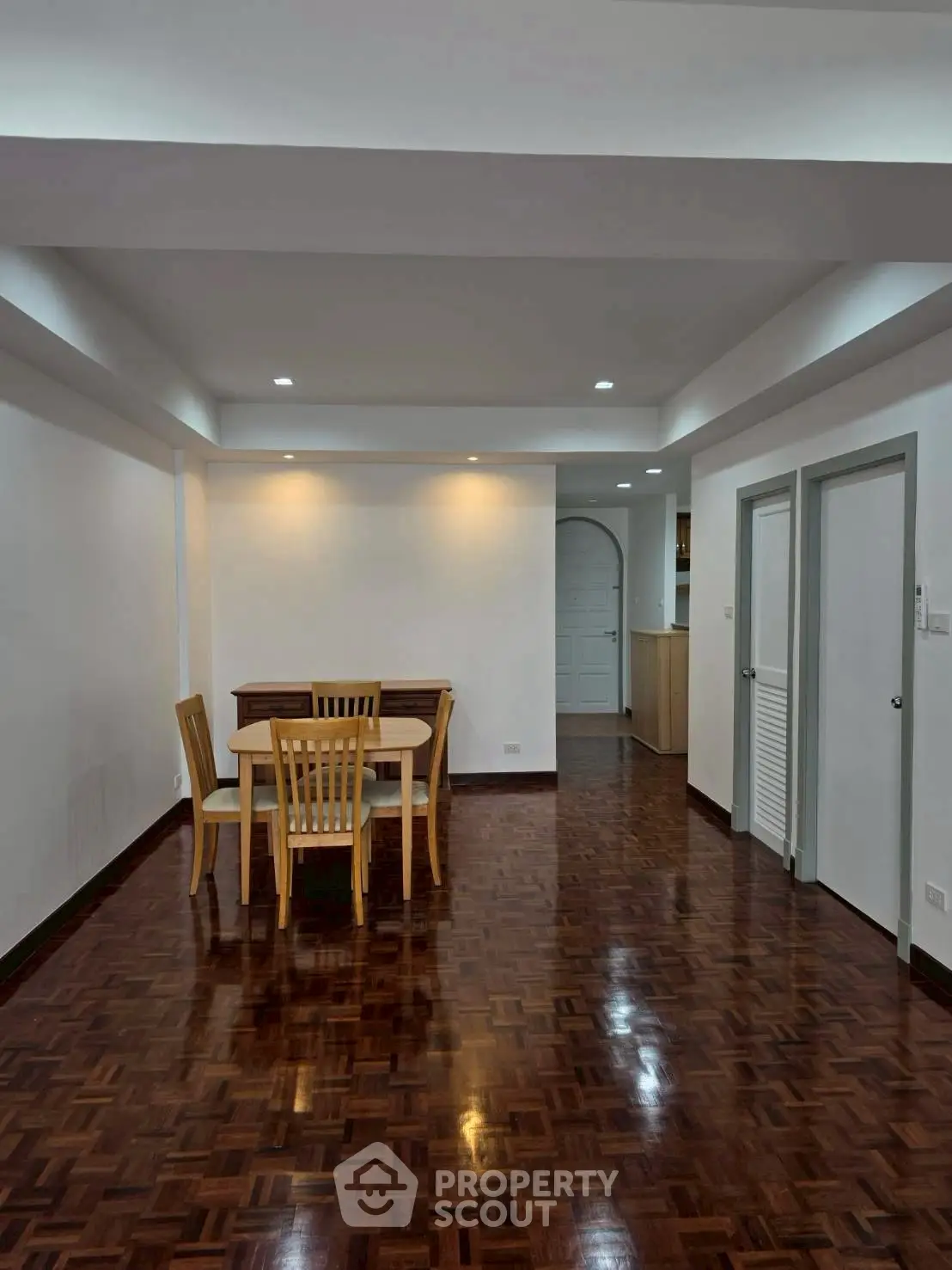 Spacious dining area with wooden flooring and modern lighting in a stylish apartment.
