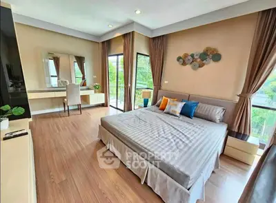 Spacious bedroom with modern decor and large windows offering lush green views.
