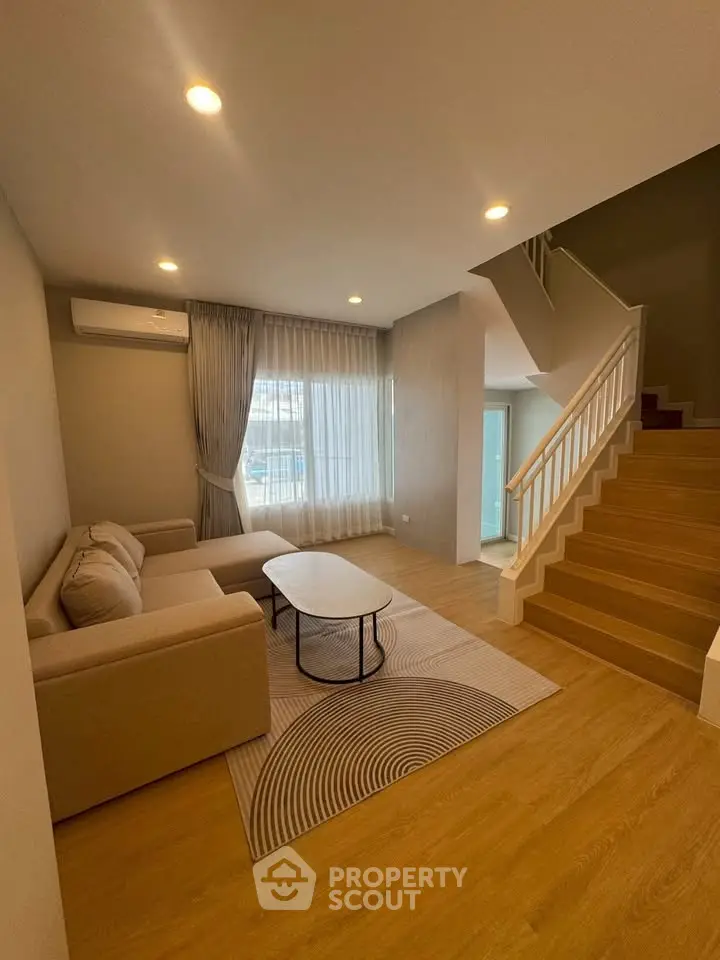 Modern living room with cozy beige sofa and stylish staircase