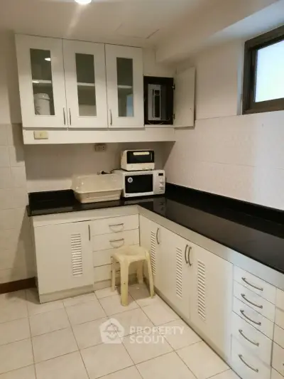 Spacious kitchen with modern white cabinetry and black countertops