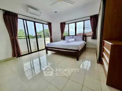 Spacious bedroom with large windows and balcony access, offering abundant natural light and serene views.
