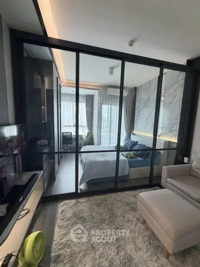 Modern studio apartment with glass partition, cozy living area, and stylish bedroom.