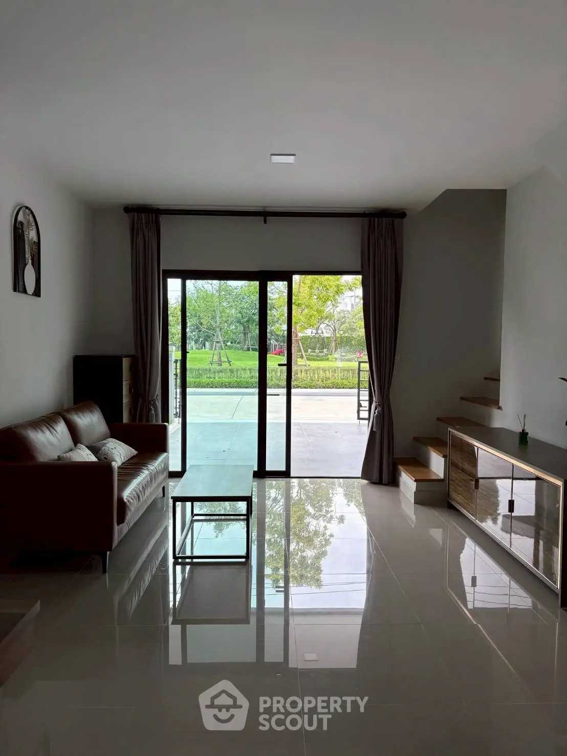 Spacious living room with modern decor and large glass doors opening to a scenic view.