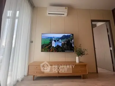 Modern living room with wall-mounted TV and stylish wooden cabinet under air conditioning unit.
