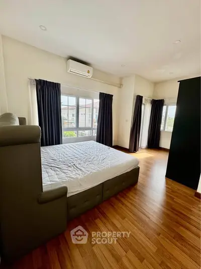 Spacious bedroom with large windows and wooden flooring, perfect for natural light lovers.