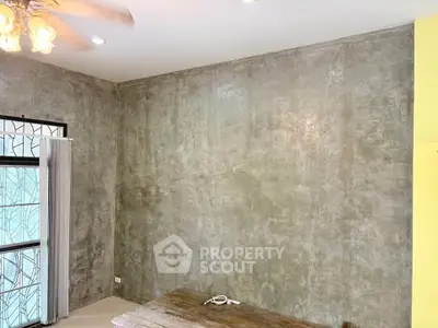 Modern industrial-style room with concrete walls and ceiling fan, ideal for creative living space.