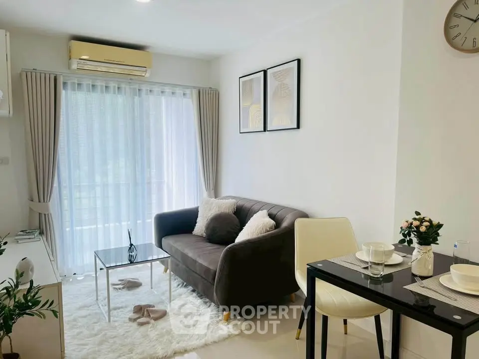 Chic modern living room with cozy sofa, elegant decor, and natural light from large window.