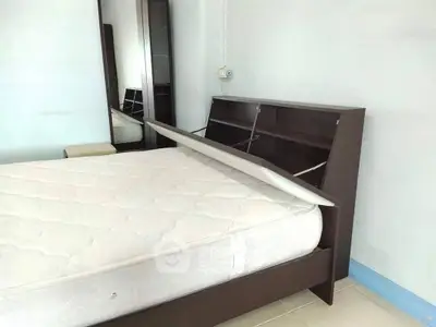 Spacious bedroom with modern bed and storage headboard, ideal for comfort and organization.