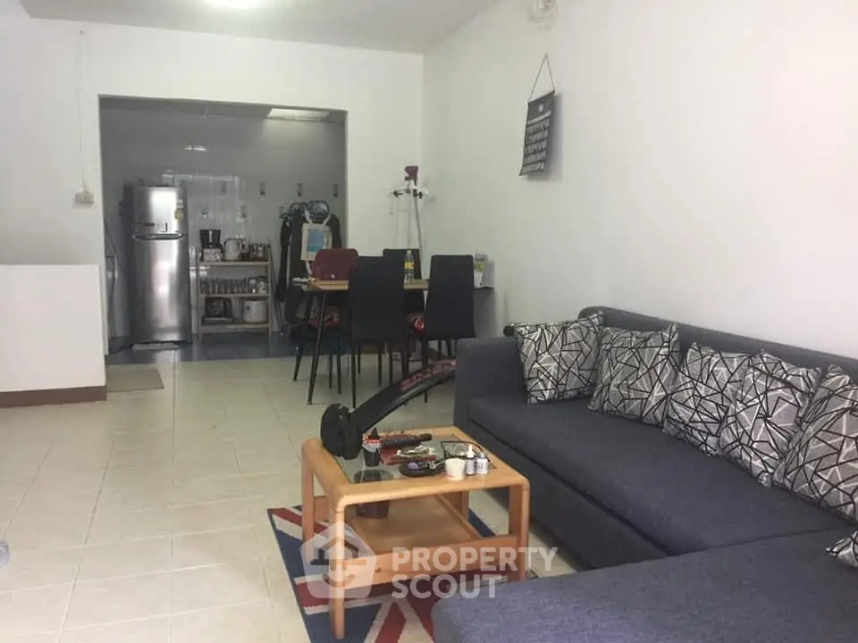 Spacious living room with modern furniture and open kitchen layout.