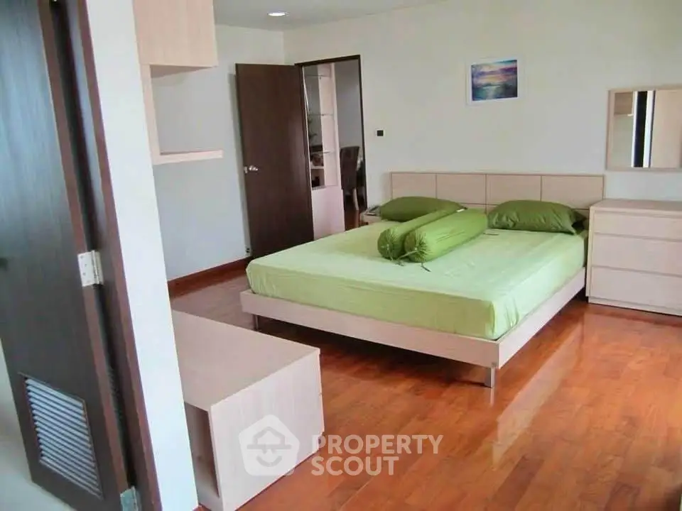 Spacious bedroom with wooden flooring and modern furniture in a stylish apartment.
