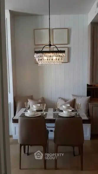 Chic dining nook with elegant chandelier and cozy seating in modern apartment.
