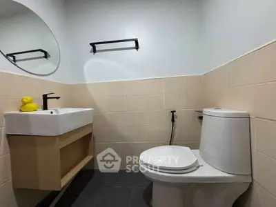 Modern bathroom with sleek fixtures and neutral tiles, featuring a stylish sink and toilet.