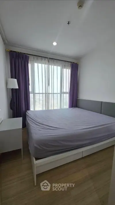 Cozy bedroom with large window and purple curtains in modern apartment