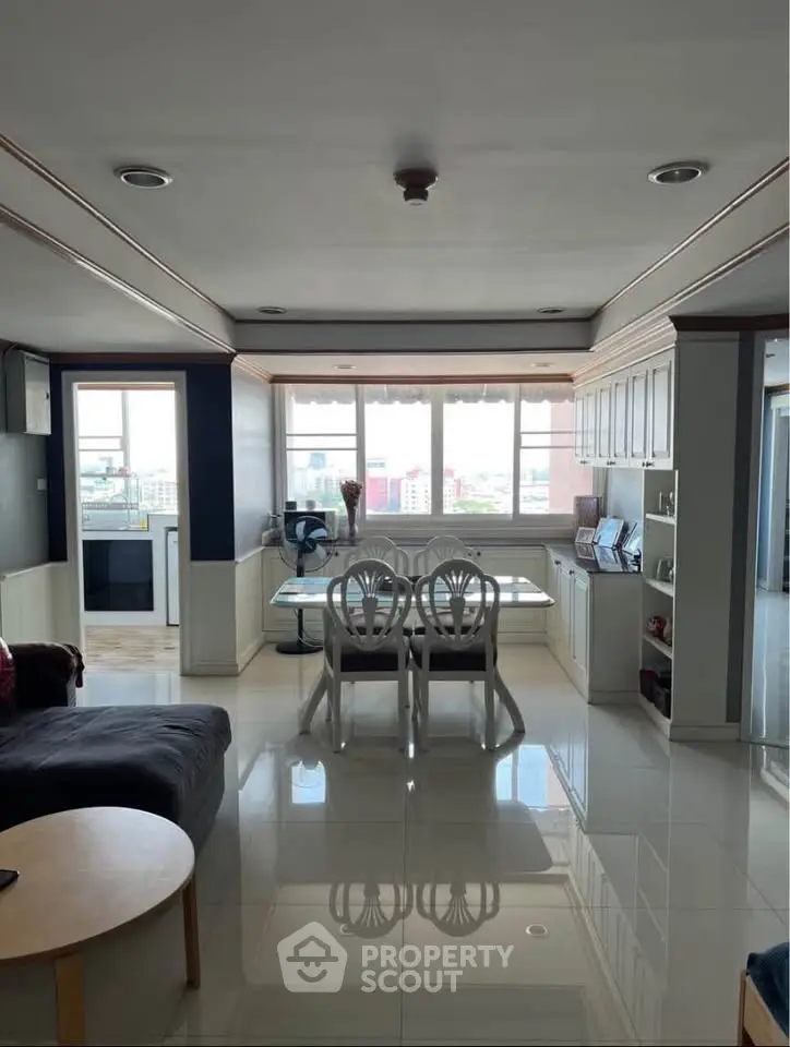 Spacious living room with dining area and large windows offering city views, perfect for modern living.