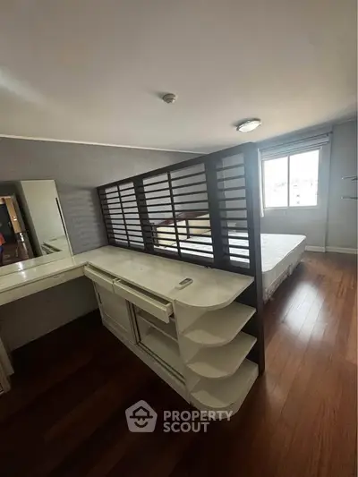 Spacious bedroom with wooden flooring and modern partition for privacy.
