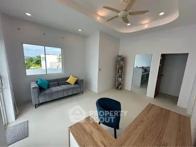 Modern living room with stylish furniture and natural light, featuring a cozy sofa and sleek wooden desk.