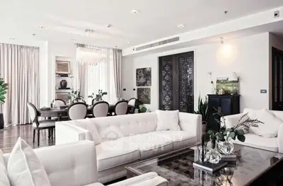 Luxurious open-plan living room with elegant dining area, featuring plush white sofas and chic decor.
