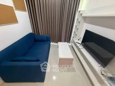 Modern living room with blue sofa, flat-screen TV, and sleek white shelving.