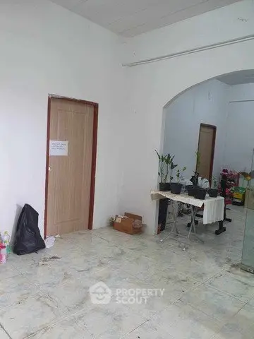 Spacious interior with tiled flooring and archway, ideal for versatile use.