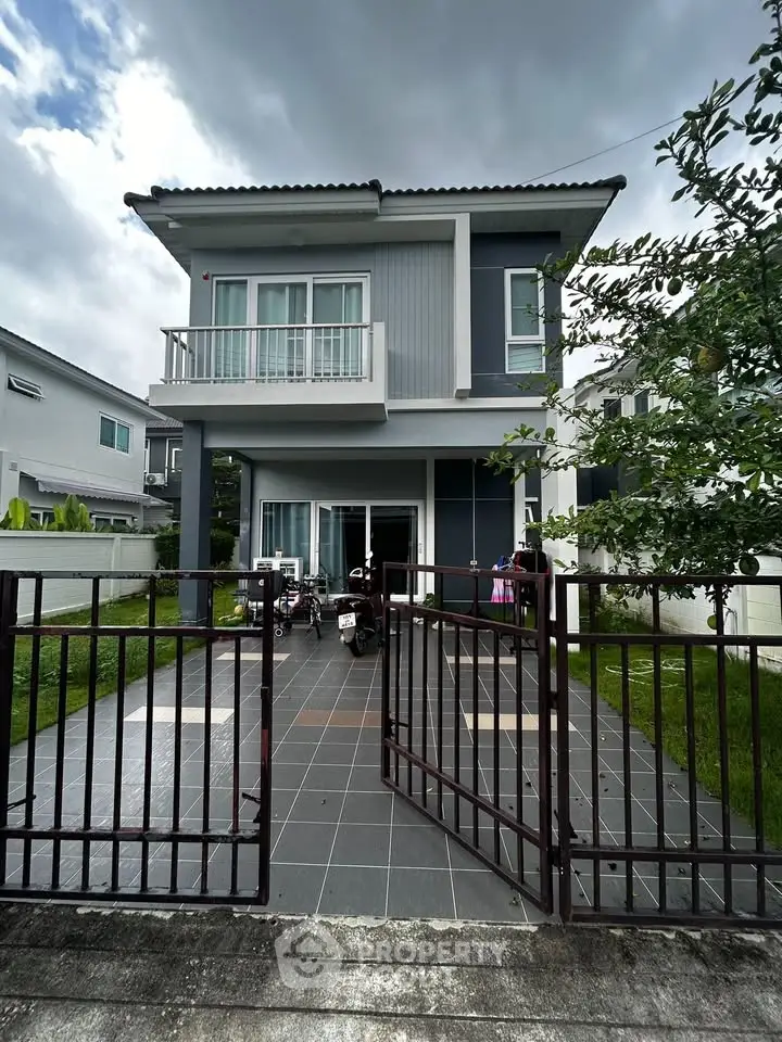Modern two-story house with gated entrance and lush greenery, perfect for family living.